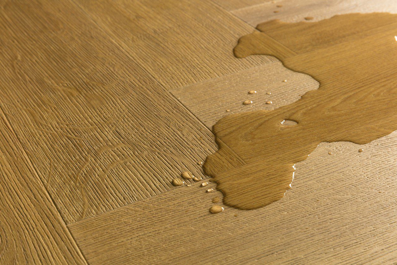 Kalanruotolaminaatti Quick Step Pergo Impressive Design Cinnamon Oak, vesilätäkkö osoittamassa vedenkestävyyttä