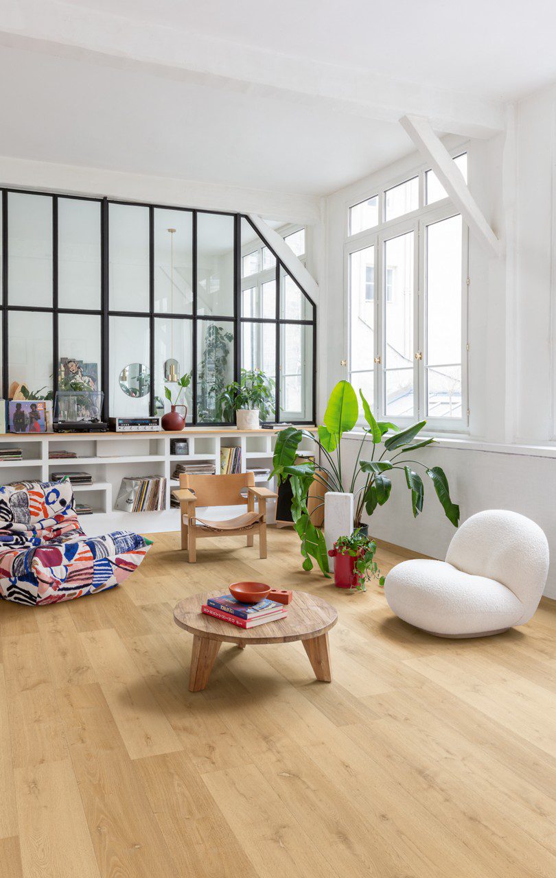 LVT parkett Quick-Step Bloom Elegant Oak Natural paigaldatud elutoa põrandale, riiul, laud, toolid ja vinüülplaadimängija.
