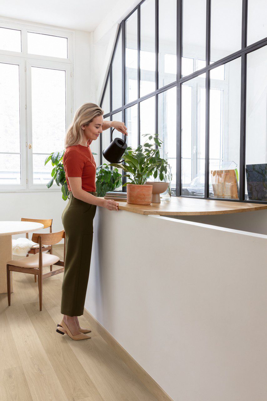Vinyl flooring Quick-Step Blos coast oak sand installed on a kitchen floor. Naine kastab potilille köögi töötasapinnal.