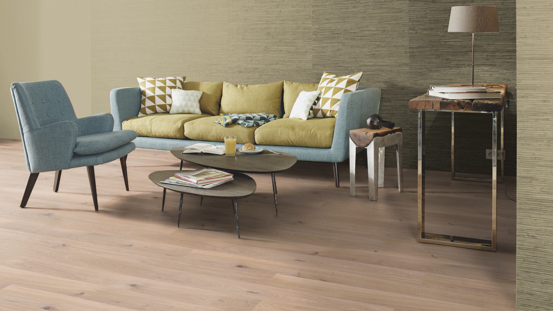 Naturaalne parkett Bauwerk Boen Casapark tamm 46 harjatud valge Farina õlivaha paigaldatud elutoa põrandale. Diivan ja tugitool ning diivanilaud millel saiake, mahl ning raamat lugemiseks.