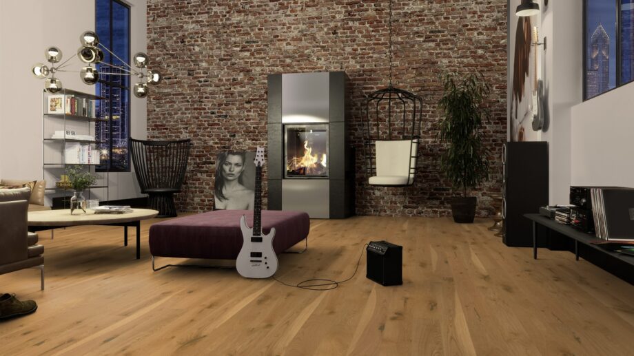 Naturaalne parkett Bauwerk Casapark Budget Cut tamm 56 faasitud 2k, harjatud 138mm paigaldatud elutoa põrandale. Vana tellisest sein, küdev kamin, diivan, diivanilaud, pehme suur tumba mille najal kitarr koos võimendiga.