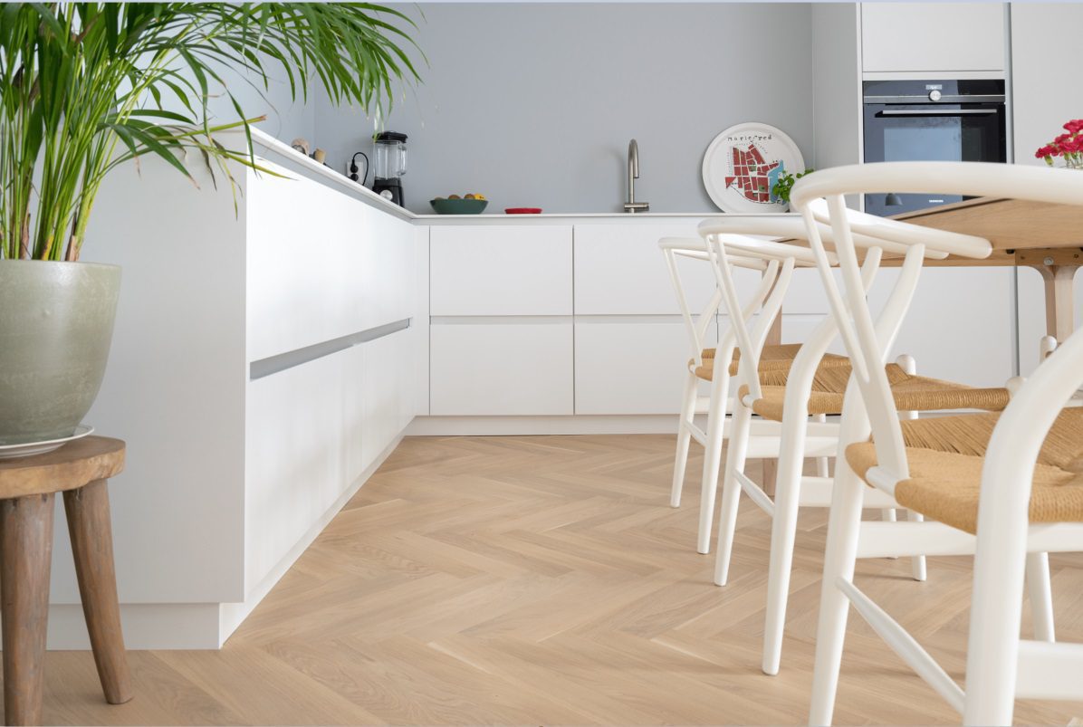 Kalasaba parkett Bauwerk Monopark Crema B-Protect® paigaldatud köögi põrandale. Valge köögimööbel, söögilaud ja toolid.