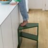 Klick Vinylboden Quick Step Bloom Botanic Beige in der Küche verlegt, ein Kind steht auf einem Stuhl und nimmt eine Orange aus einer Obstschale auf der Kücheninsel.