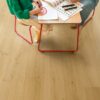 Klickvinyl Quick Step Bloom Brushed Oak Honey im Kinderzimmer verlegt, Tochter und Vater sitzen am Tisch und zeichnen.