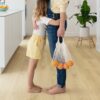 LVT põrandakate Quick-Step Bloom Botanic Beige paigaldatud köögi põrandale. Tütar kallistab ema kellel on käes kilekott apelsinidega.