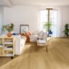 Vinyl flooring Quick-Step Bloom Brushed Oak Honey installed on a Livingroom floor. Sofa, table, shelves.