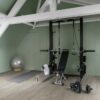 vinyl-flooring-quick-step-bloom-cotton-oak-cozy-grey Quick Step Bloom Cotton Oak Cozy Grey vinyl flooring installed in a home gym, with strength training equipment.