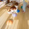 Vinylboden Quick Step Bloom Brushed Oak Honey im Wohnzimmer verlegt, Kind spielt mit einem Hund.