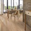 Fertigparkett Bauwerk Boen Casapark Eiche 46 Vivo (138 mm), gebürstet und mit Osmo Hartwachs-Öl geölt – verlegt im Flur und Essbereich; Holzesstisch mit Holzstühlen und gedecktem Tisch, rustikale Flurwände in Betonoptik. Rustikale Sortierung mit lebendiger Maserung und Astanteilen.