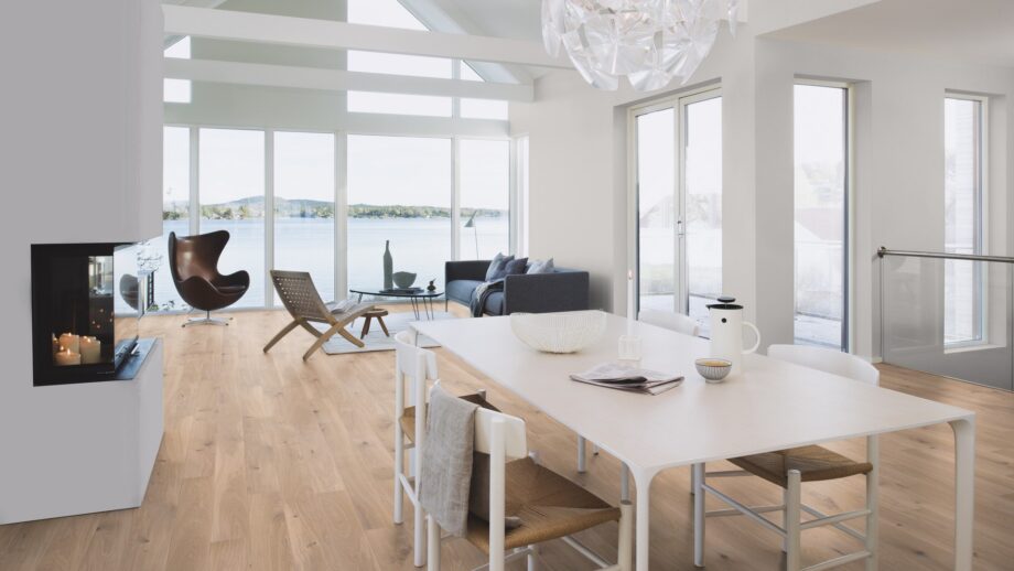 Parquet floor Bauwerk Boen Casapark Oak 46 brushed Farina white oiled installed on a living room floor. Sofa, chair, fireplace, dining table with stools.