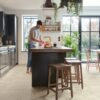 Vinyl flooring tiles Quick-Step Illume Pebble concrete installed on a kitchen floor. Man is washing apples.