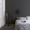 Vinyl flooring tiles Quick-Step Illume Soft graphite with dark grey color installed on bedroom floor. King size bed.