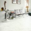 vinylboden-stein-quick-step-oro-marble-carrara-white Vinylboden Stein Quick Step Oro Marble Carrara White im Wohnzimmer verlegt heller Carrara Marmor Look in Weiß mit feiner grauer Maserung braune Stühle mit Lederbezug runder Tisch und eckiger Tisch mit goldener Tischleuchte
