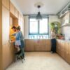 Vinyylilattia Quick-Step Illume Pebble Concrete asennettuna keittiön lattialle – nainen kaataa kahvia, ja isä sekä tytär puristavat yhdessä appelsiinimehua; vaalea greige/betonisävy ja hillitty betonikividesign.