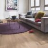 Laudparkett Bauwerk Casapark tamm 46 Crema harjatud ja heleda Bprotect lakiga viimistletud. Parkett on paigaldatud elutoa põrandale. Kaks diivanit ja disainer diivanilaud millel kauss kartulikrõpsudega, veepudel ja veeklaasid. Diivainilaua all on ümar tükivaip.