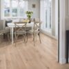 Naturaalparkett Bauwerk Casapark tamm 46 Crema harjatud ja heleda ultra mattlakiga viimistletud. Paigaldatud klassikalises stiilis söögitoa põrandale. Klassikaline valge söögilaud millel valged lilled. Toolid ja diivan söögilaua ümber.