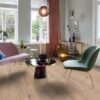 Puitparkett Bauwerk Casapark tamm 46 Crema harjatud heleda Bprotect ultra mattlakiga viimistletud paigaldatud elutoa põrandale. Tool, diivan ja klaasist diivanilaud.
